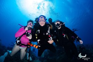 Group of smiling Blue Horizon divers posing together in blue water above the reef